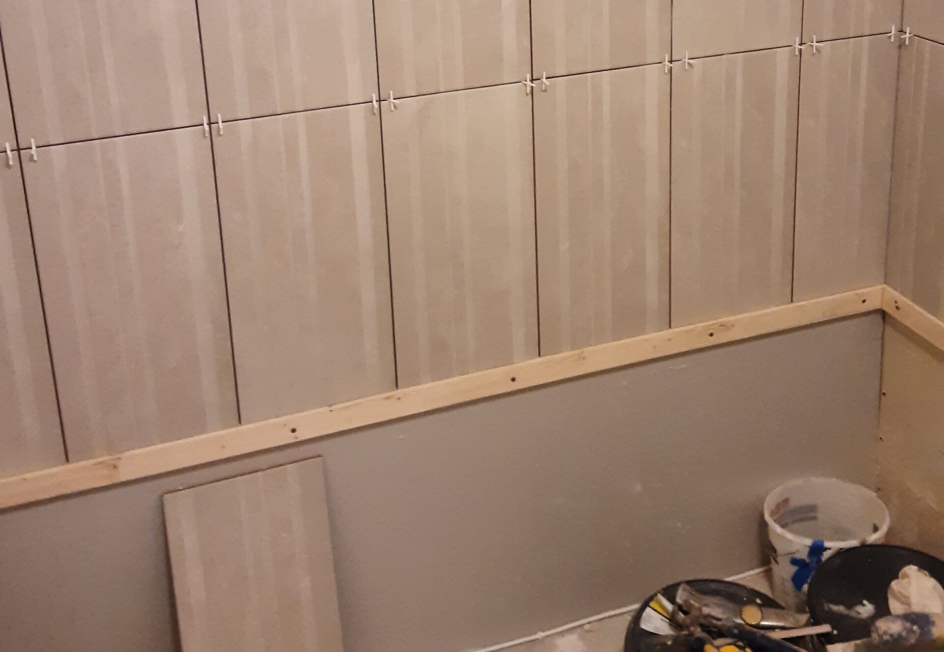 Photo of accessible bathroom build showing the tiling process underway