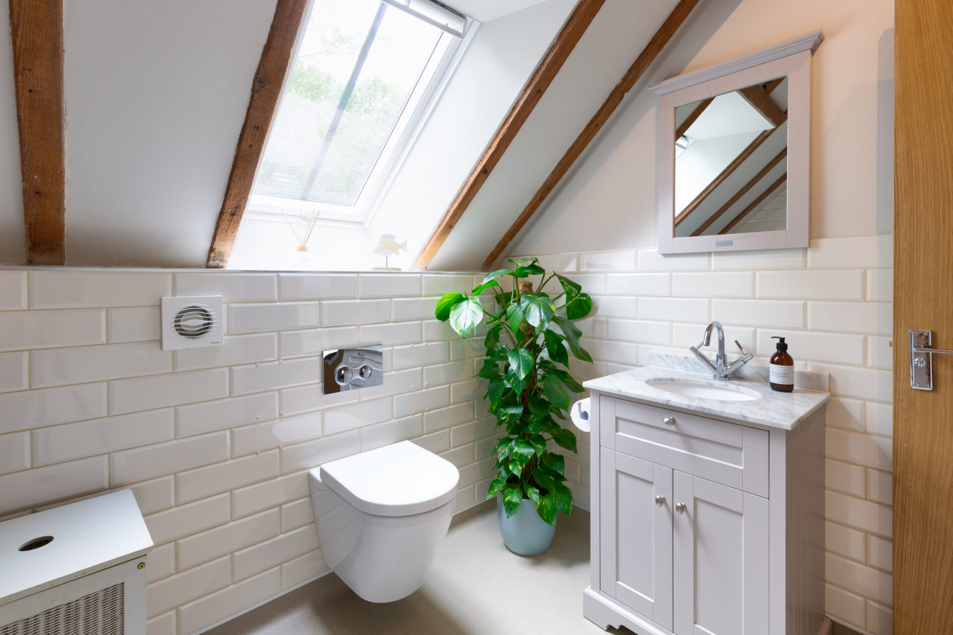 Image of accessible bathroom adaptation in barn with vaulted ceiling. Focus on vanity with marble top and matching mirror