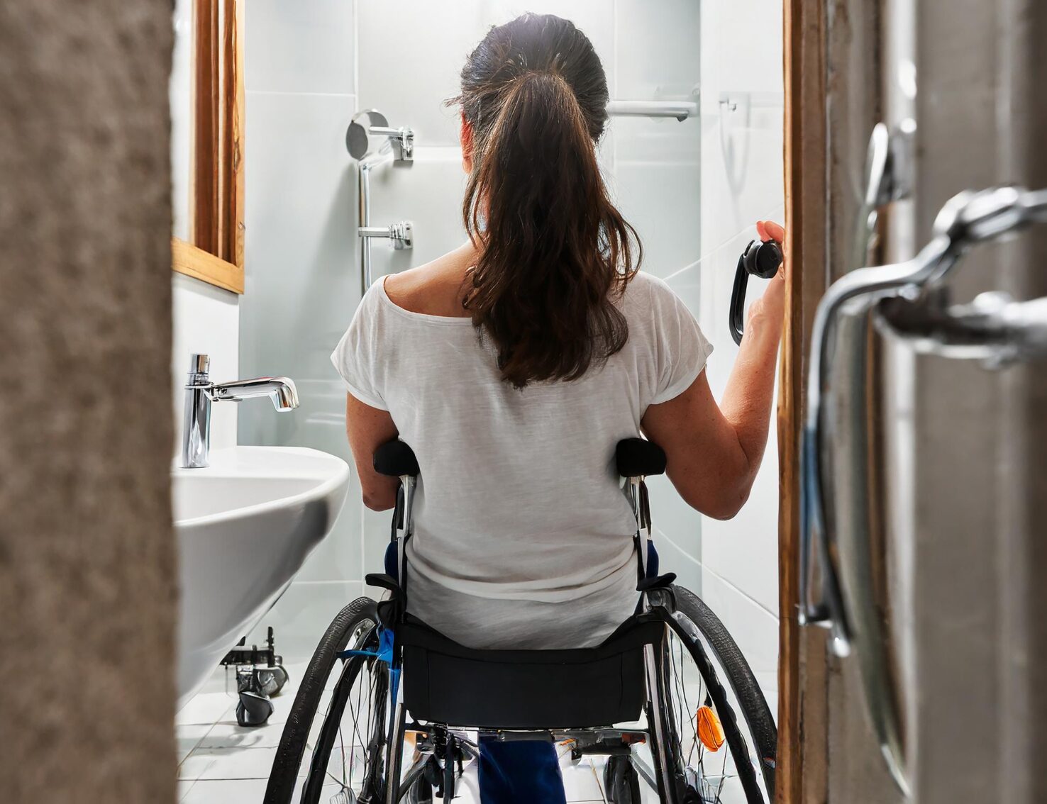 Photo of woman sitting in wheelchair accessing a small wheelchair accessible bathroom