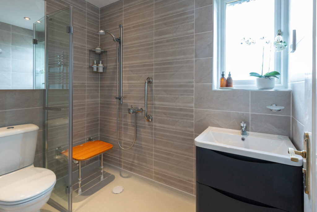 Photo showing a luxurious walk-in shower room with folding shower seat and space saving storage