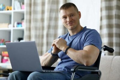 Portrait Of Smiling Disabled Male Sitting In Wheelchair And Work