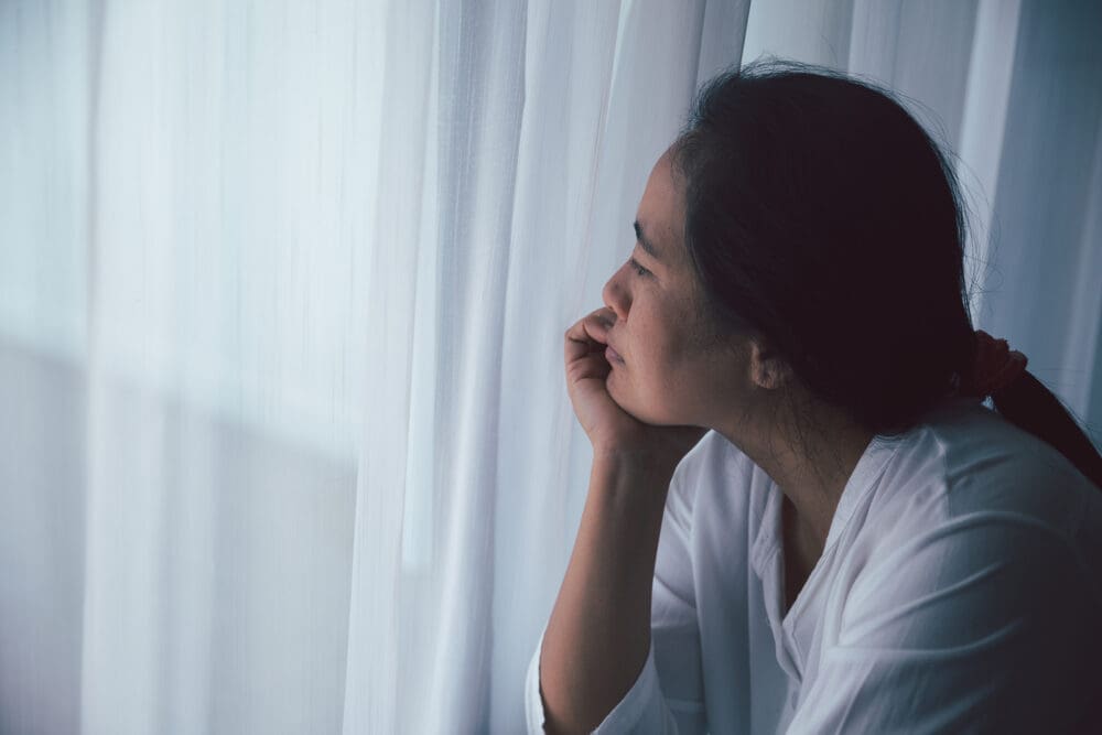 Schizophrenia with lonely and sad in mental health depression concept. Depressed woman sitting against floor at home with dark room feeling miserable. Women are depressed, fearful and unhappy.