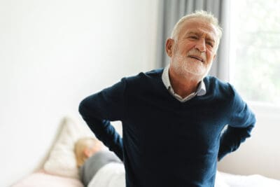 Sick unhappy senior adult elderly man touching her muscle injury Lower back suffering from muscles back pain at home.physical injury and healthcare problem