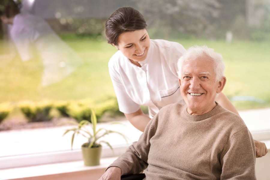 Carehome with nursing assistant helping an elderly gentleman in a wheelchair