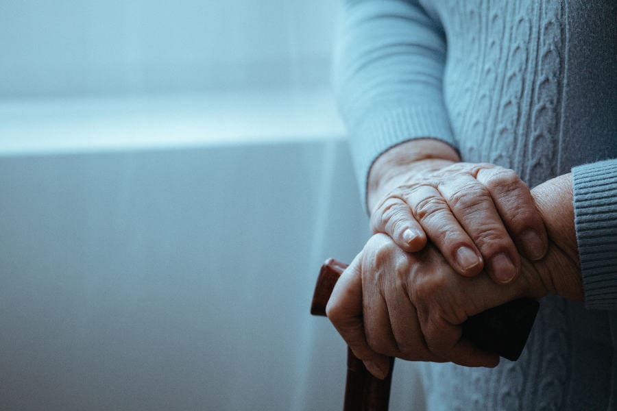 elderly womans hands on walking stick