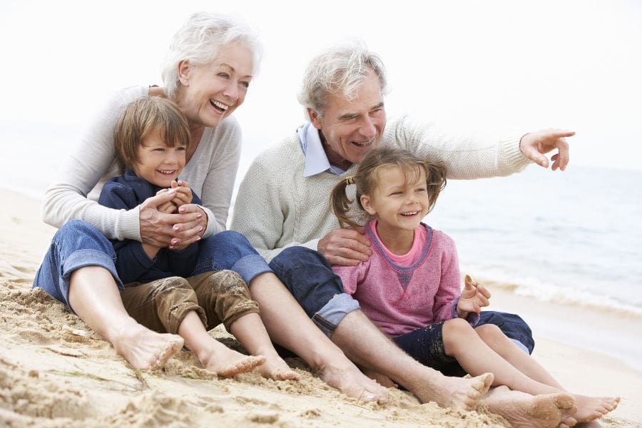 grandparents and children sitting on beach